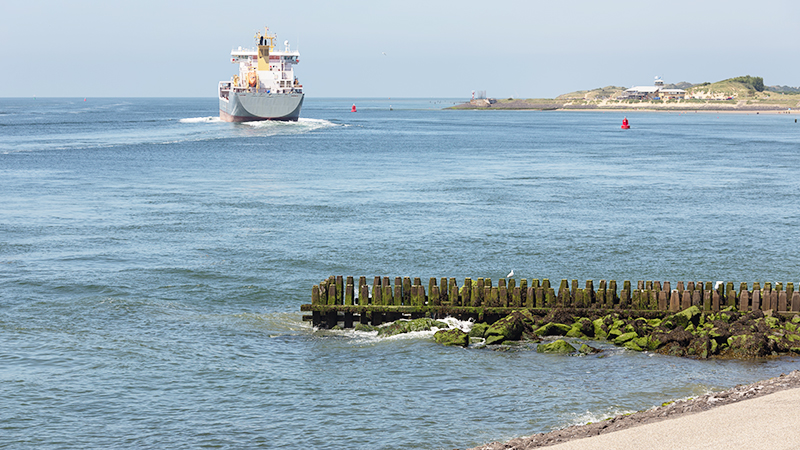 Dutch waterside of Vlissingen with a cargo ship sailing close to the coast